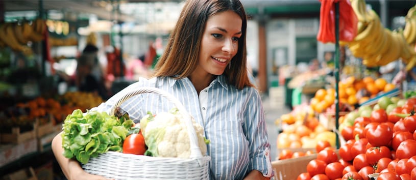 woman holding groceries basket full of vegetables