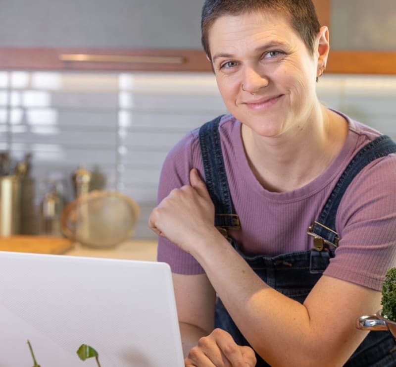 person smiling in kitchen with laptop