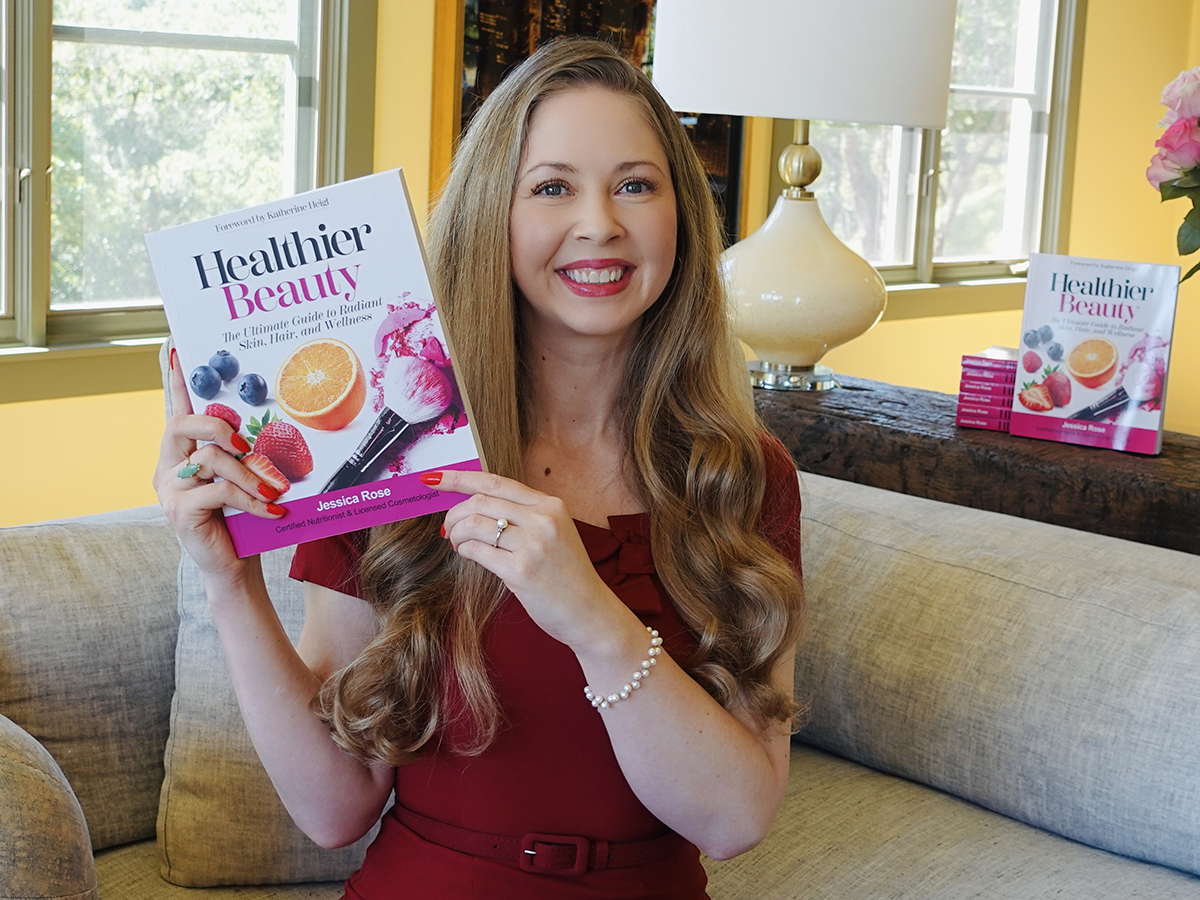 Bauman College Grad and Author, Jessica Rose holding a copy of her book, Healthier Beauty