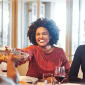 Woman passing a plate across dining table