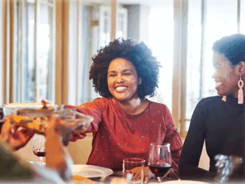Woman passing a plate across dining table